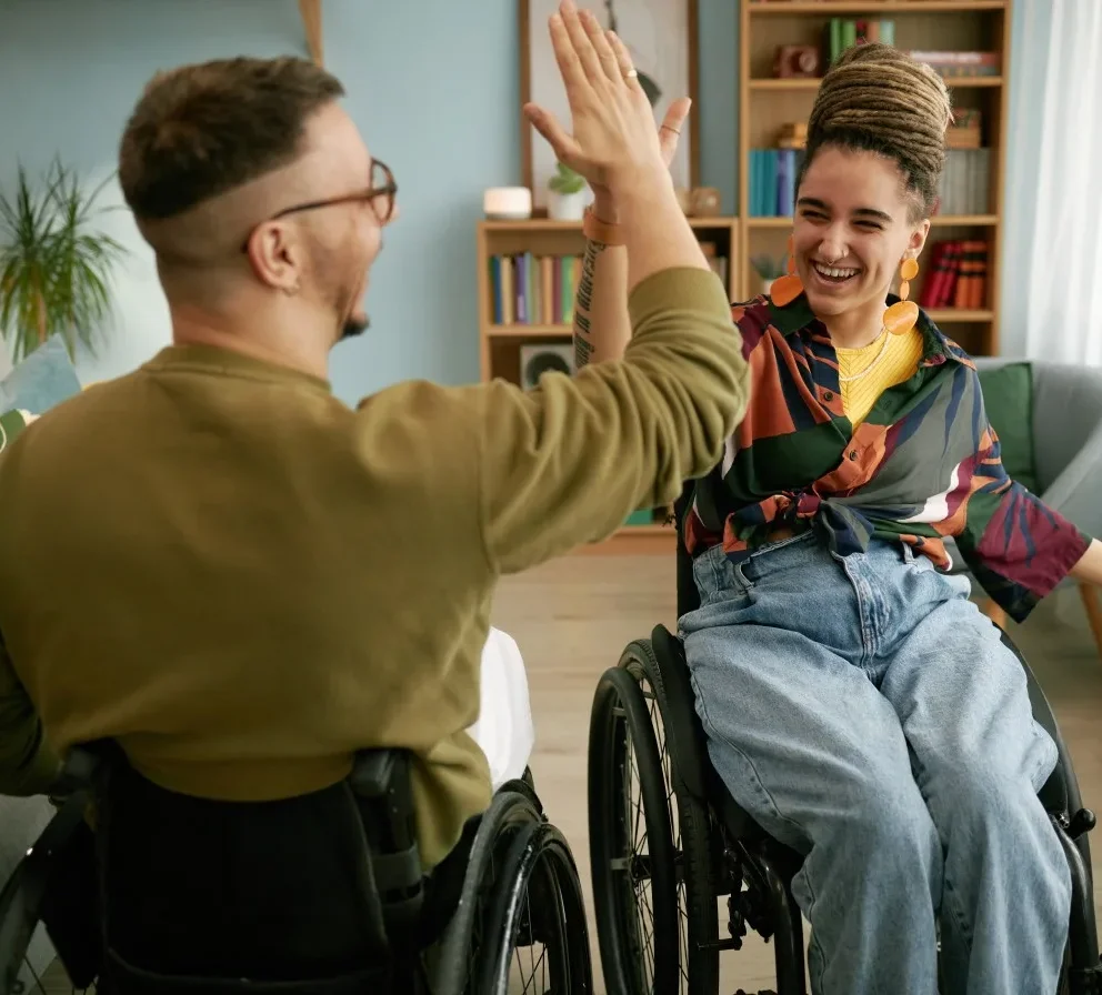 Two disabled friends in wheelchairs high fiving