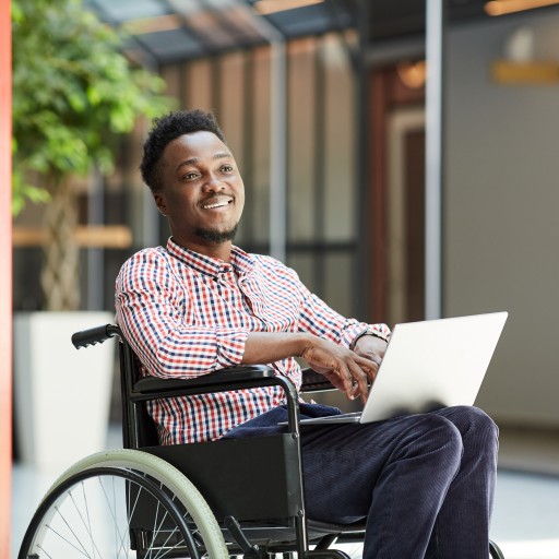Disabled man in wheelchair using laptop