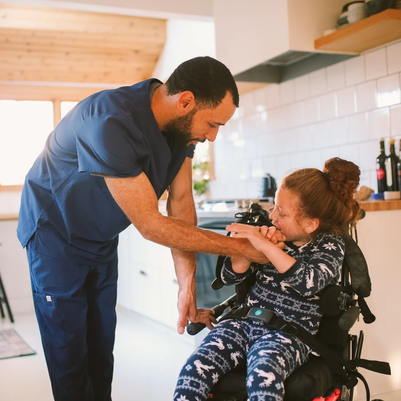 Support worker helping disabled girl in wheelchair