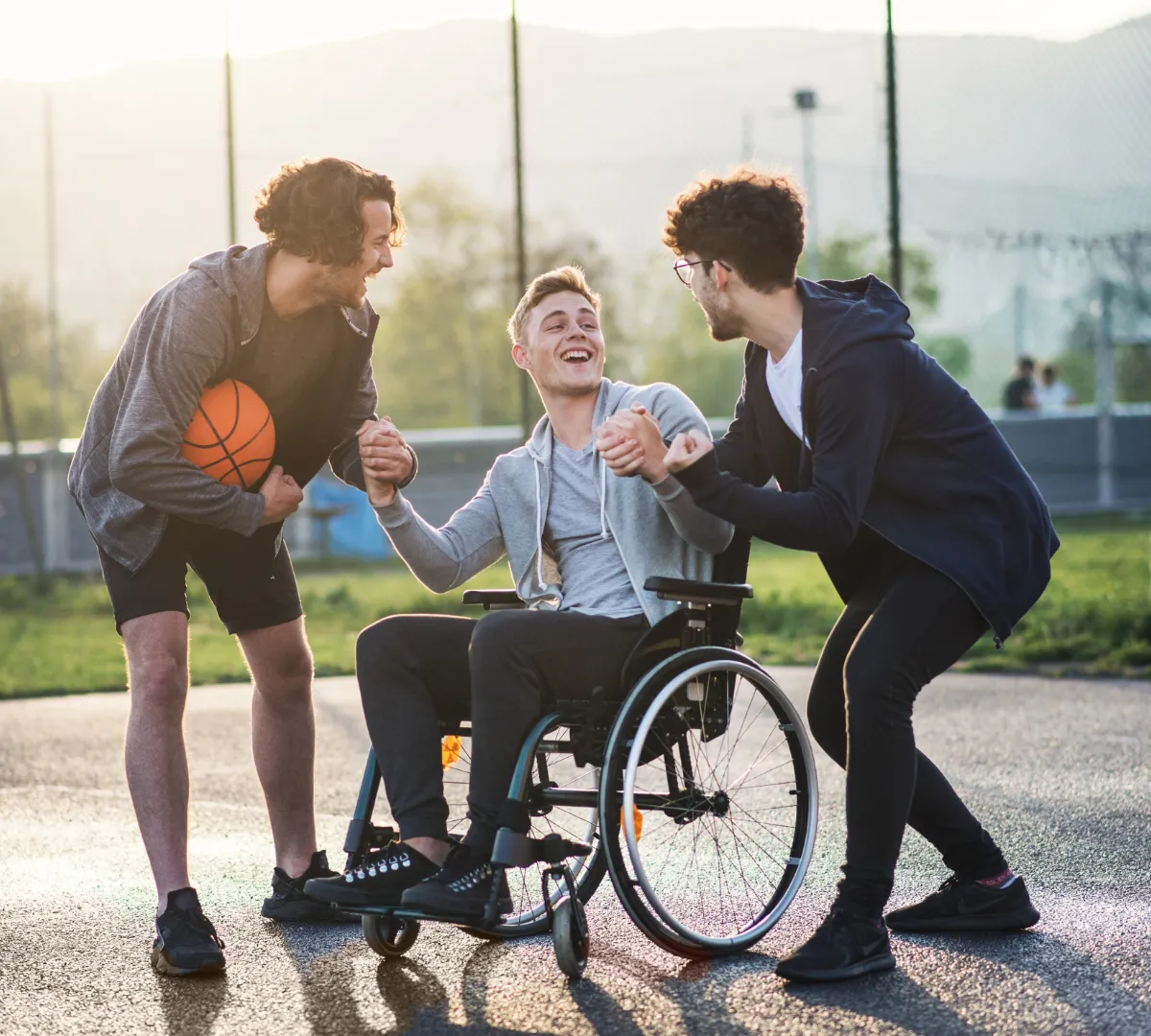 Disabled man in wheelchair playing basketball with two friends